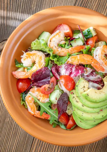 Canlı salata karidesleri avokado taze yeşiller narenciye soslu ahşap masa kırsalları.