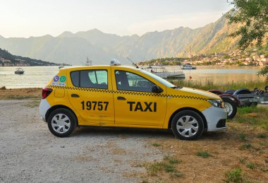 Kotor, Montenegro - June 7, 2022: Yellow taxi parked on the beach. The bay of Kotor. Montenegro