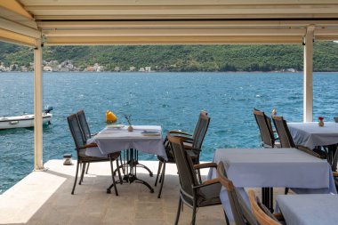 Tables and chairs overlooking the Bay of Kotor in a typical seaside restaurant in Montenegro