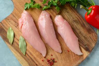 Kesme tahtasındaki çiğ hindi fileto eti parçaları.