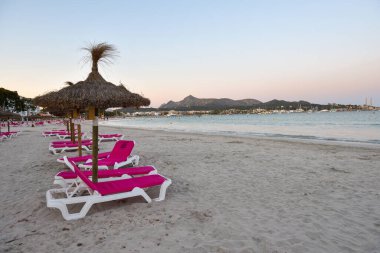 Alcudia, Mallorca - 4 Mayıs 2019: Alcudia, Mallorca 'nın kumlu plajında şemsiyeli güneş panzeleri