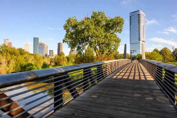 Rosemont yaya köprüsü Buffalo Bayou 'nun üzerinden geçiyor Houston şehir merkezindeki gökdelenleri görüyor. Teksas, ABD