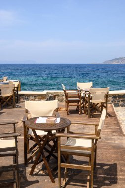 Nisyros adasındaki tipik bir Yunan sahil restoranında masa ve sandalyeler. Yunanistan