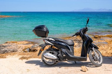 Ano Koufonisi, Yunanistan - 15 Mayıs 2024: Ege Denizi kıyılarına park etmiş bir scooter. Ano Koufonisi, Cyclades, Yunanistan
