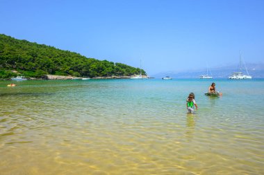 Brac, Hırvatistan - 12 Haziran 2025: Çocuklu aileler için ideal sığ sulara sahip kumlu Lovrecina Sahili. Hırvatistan 'ın Brac adasının kuzey kıyıları