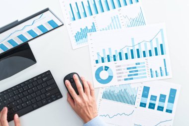 Top view of business man using spreadsheet. Many business analysis reports and desktop computer.