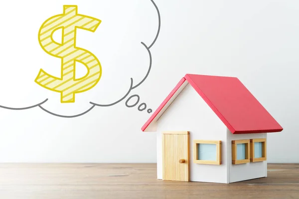 房子和钱在气球中的迷你房子和插图美元标志 木制书桌和白色背景 免版税图库图片