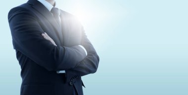 Çapraz kollu kendine güvenen bir işletme yöneticisi. Arka ışıklandırmalı açık mavi arkaplan