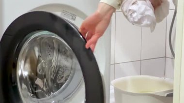 Kirli Çamaşırları Çamaşır Makinesi 'ne yüklemek. Kirli beyaz elbiseleri çamaşır makinesine koyan bir kadının orta pozu..