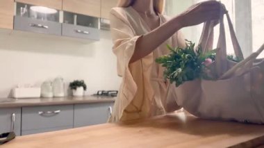 Ev Mutfağı 'nda içi taze sebze dolu alışveriş torbası olan bir kadın..