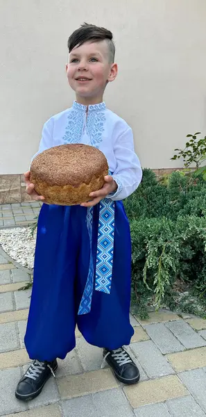 Geniş pantolonlu çocuk ekmek tutuyor.