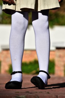 Kadın çocuk etek ve beyaz çorap giyiyor.