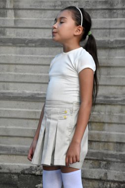 Güzel Filipinli çocuk merak ediyor etek giyiyor duvarın yanında duruyor