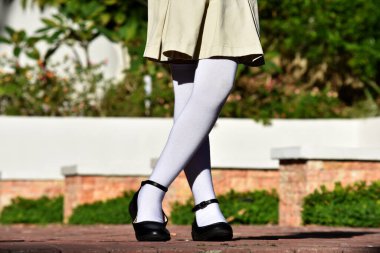 Kadın çocuk etek ve beyaz çorap giyiyor.