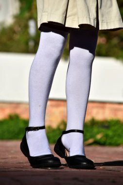 Kadın çocuk etek ve beyaz çorap giyiyor.
