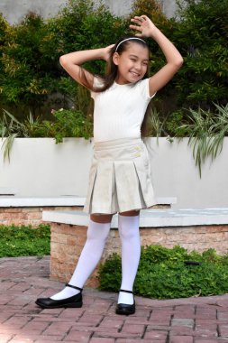 Genç Philippina kılığına girmiş, etek giymiş, Park 'ta duruyor.