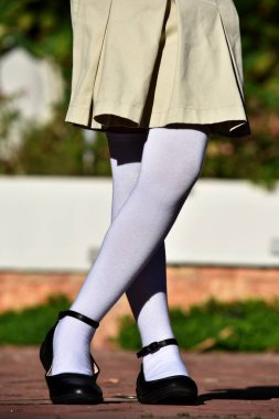 Kadın çocuk etek ve beyaz çorap giyiyor.