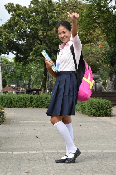 Cute Girl Student With Thumbs Up Wearing Uniform With Books Standing