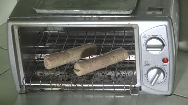 烤面包机烤箱中的未烹调香肠 — 图库视频影像