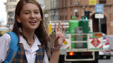 Sırt çantası ve sırt çantasıyla şehirde yürüyen genç bir kız.