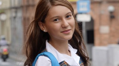 Genç kız gülümsüyor ve başka tarafa bakıyor.