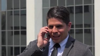 Dışarıda cep telefonuyla konuşan yakışıklı bir iş adamı.