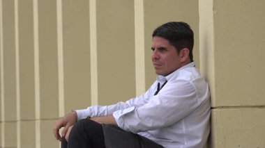 Duvara yaslanan düşünceli adam.