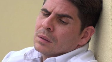 Endişeli erkek duvarda oturuyor.