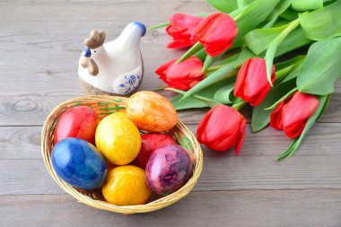Kırmızı laleler, paskalya yumurtaları ve ahşap bir arka planda hasır bir sepetin içinde bir Alman..