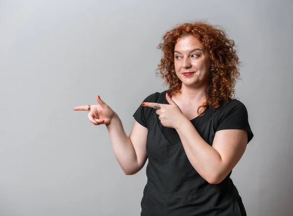 stock image Happy woman with red curly hair posing on grey background, with copy space showing with hands