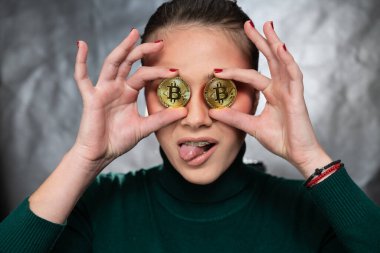 Elinde bitcoin tutan güzel bir kadın, farklı yüz ifadeleriyle, stüdyo çekimi.