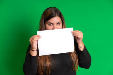 Elinde boş bir kağıt olan genç bir kadın, yeşil arka planda herhangi bir renk kolayca değiştirilebilir.