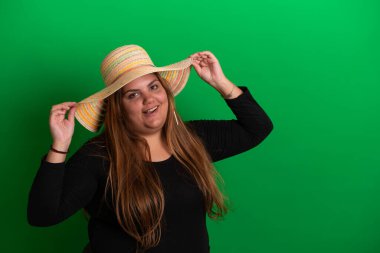 Yeşil arka planda, yaz şapkası takan genç bir kadın.