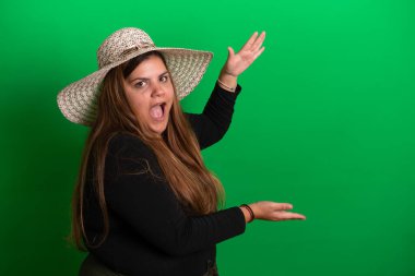 Yeşil arka planda, yaz şapkası takan genç bir kadın.