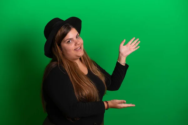 stock image Young woman, wearing black hat, gestures with hands   Green Background is easy to change to any colour