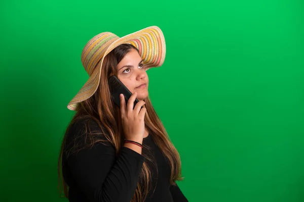 戴着夏帽的年轻女性 使用智能手机绿色背景 — 图库照片
