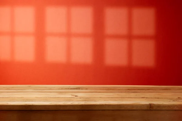 空荡荡的木制桌子盖着时髦的红墙背景 窗上有阴影 为设计和产品展示模拟寒假 — 图库照片
