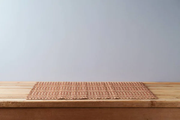 灰色の壁の背景に木製のテーブルの上に竹の場所マット デザインや製品表示のためのキッチンモックアップ — ストック写真