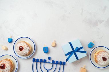 Background with traditional sweet donuts, menorah and gift box.  Hanukkah holiday concept. Top view, flat lay clipart