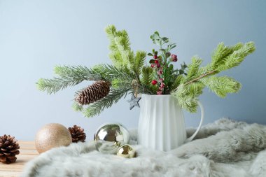 Vazoda çam ağacı dalları ve parlak arkaplanda süslerle Noel masası dekorasyonu