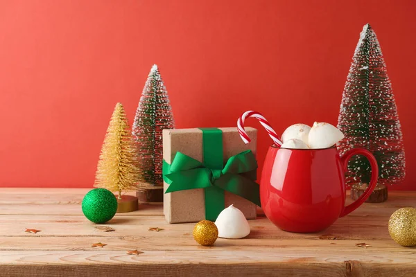 赤い背景の上に木製のテーブルの上にマシュマロとクリスマスの装飾が施されたクリスマスホットチョコレートカップ — ストック写真