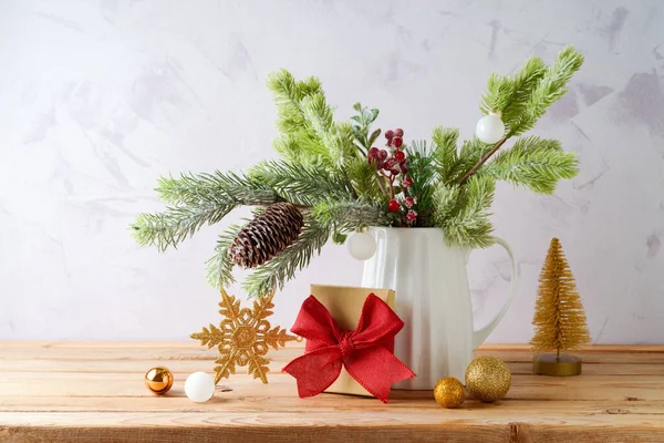 明るい背景に木製のテーブルの上に花瓶 ギフトボックスと黄金の装飾で松の木の枝とクリスマスの装飾 — ストック写真