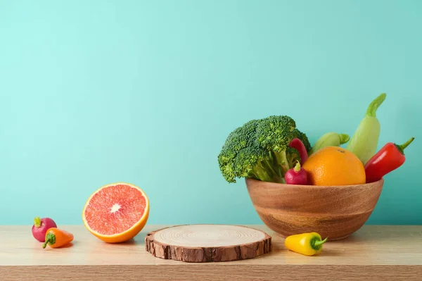 Empty wooden log with vegetables and fruits on table over blue wall  background. Vegetarian kitchen interior mock up for design and product display