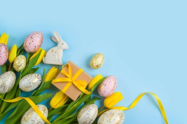 Easter holiday background with easter eggs, gift box and yellow  tulip flowers. Top view, flat lay