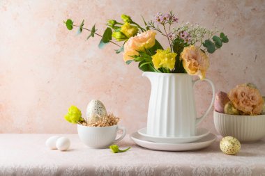 Paskalya bayramı kutlaması çiçek buketi ve Paskalya yumurtası süslemesi ile taş duvar arkasında.