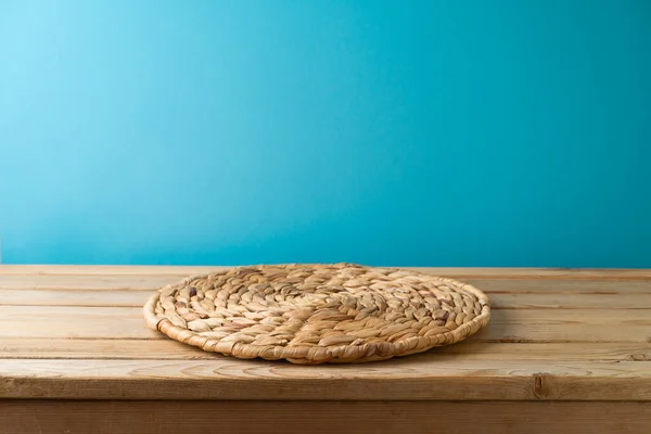 Prázdný Dřevěný Stůl Proutěnou Podložkou Přes Modré Pozadí Stěny Kuchyňský — Stock fotografie