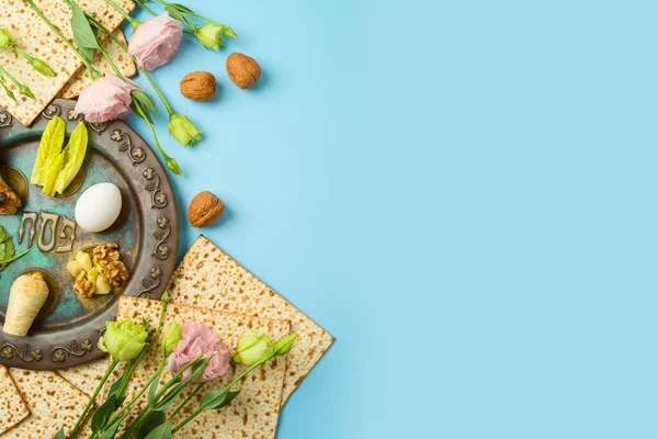 ユダヤ人の休日マツァ セダープレートと青の背景に春の花と過越のお祝いのテーブル設定 トップビュー フラットレイアウト — ストック写真
