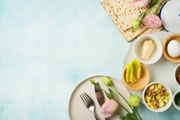 ユダヤ人の休日マツァ セダープレートと青の背景に春の花と過越のお祝いのテーブル設定 トップビュー フラットレイアウト — ストック写真
