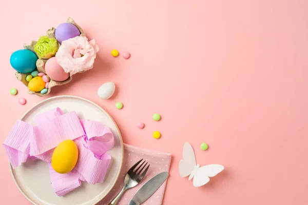 ピンクの背景にプレート イースターの卵やパーティーの装飾とイースターの休日のお祝いのテーブルの設定 トップビュー フラットレイアウト — ストック写真