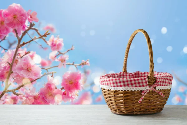 木制桌子上的空野餐篮盖着樱花背景 春天和东方的设计模型 — 图库照片